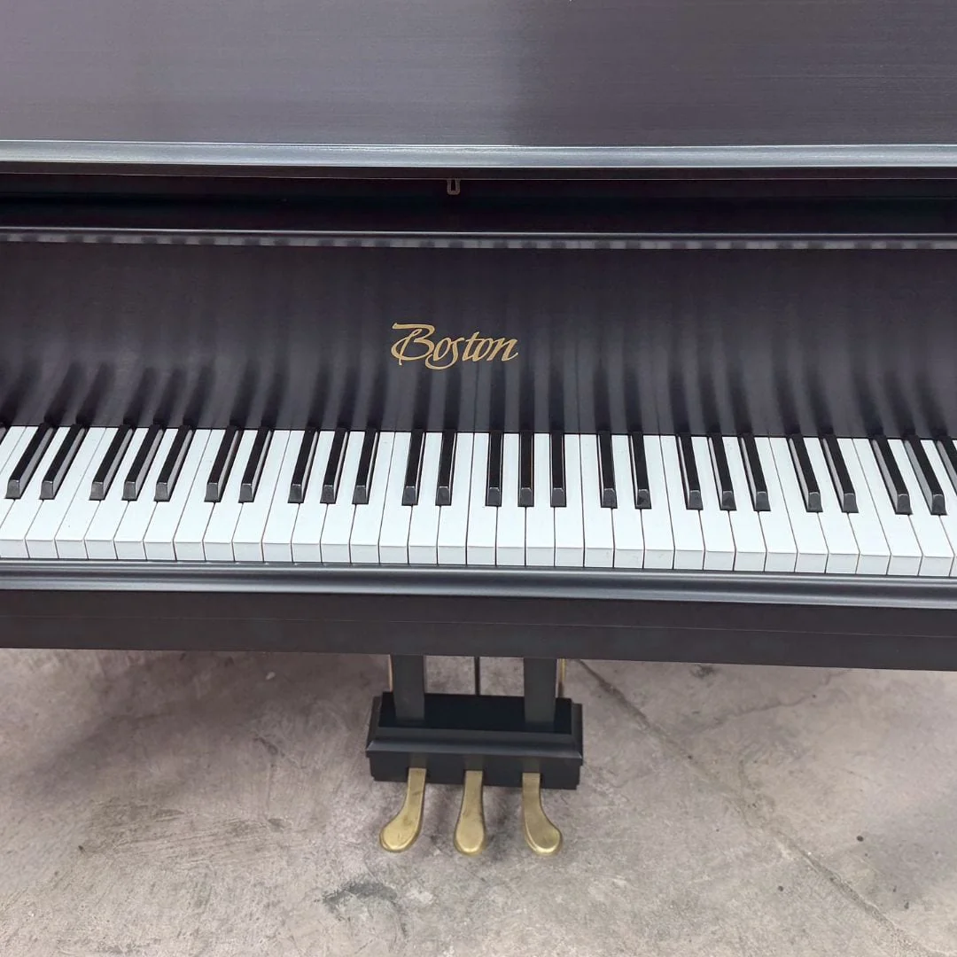The restored Boston grand keyboard straight on, with the gold Boston decal and brass pedal lyre
