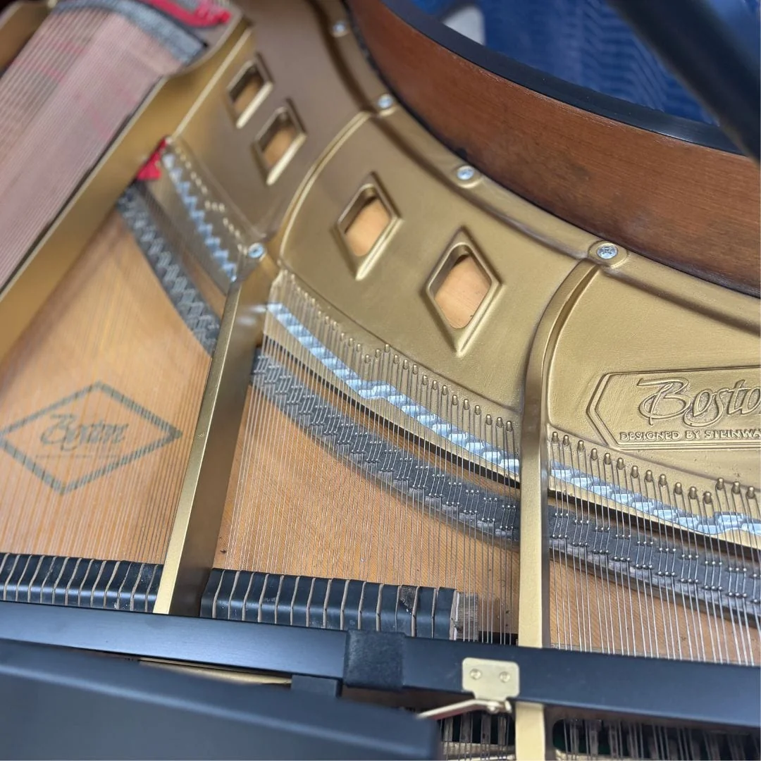 The gold plate cast with "Boston, designed by Steinway", above the soundboard and fresh stringing