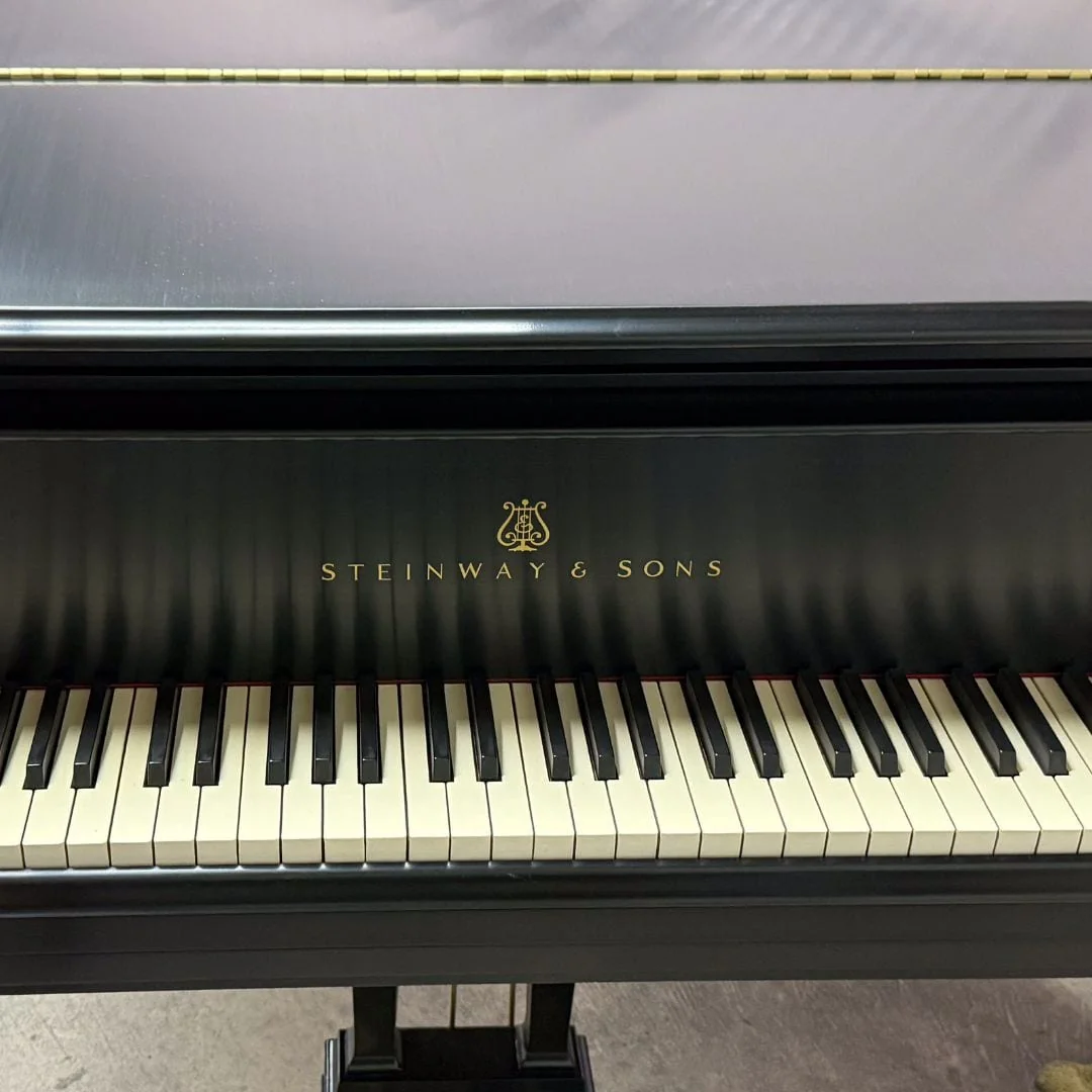 The restored Steinway Model M keyboard straight on, with the gold Steinway & Sons decal and brass pedal lyre